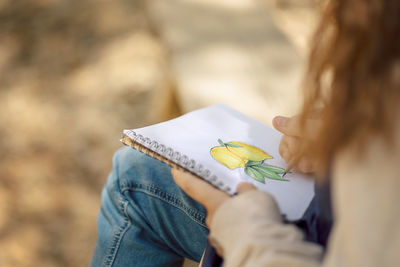 Little girl paints in open air in spring blooming fairytale park. children's drawings. creative kid. 