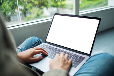 Midsection of woman using laptop on table