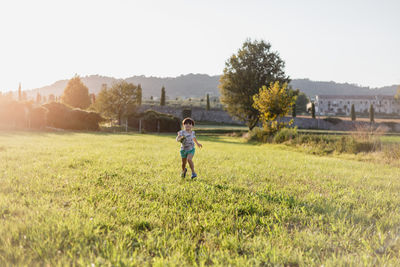Rear view of woman walking on field against clear sky