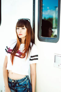 Young woman standing by camper trailer