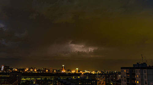 Panoramic view of city against dramatic sky at night