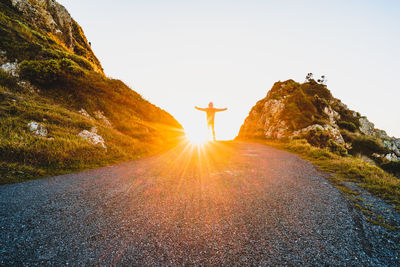 Rear view of person walking on road against clear sky