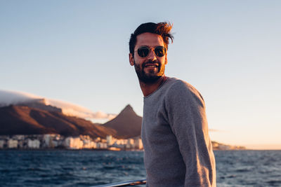 Young man standing in boat on sea against sky