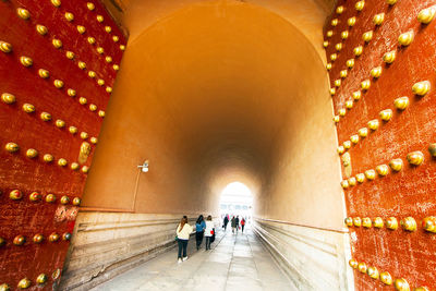 Rear view of people walking in tunnel