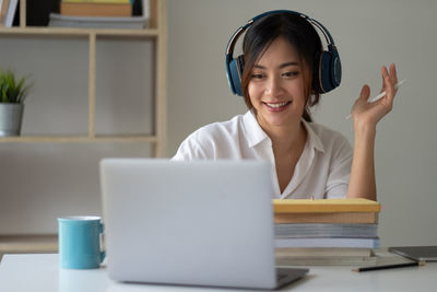 Young woman using laptop while sitting on table