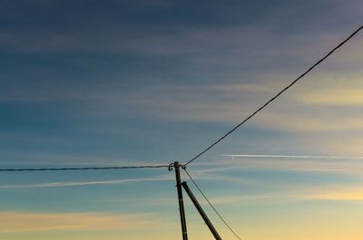 Low angle view of electricity pylon against sky during sunset