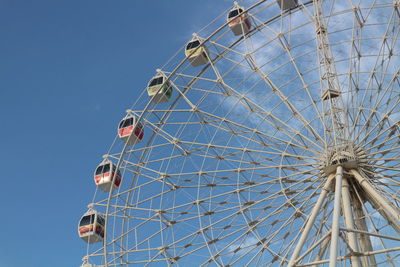 Low angle view of ferris wheel against clear blue sky