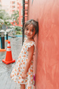 Portrait of cute girl standing against wall