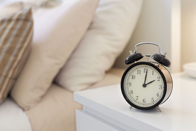 Close-up of clock on table by bed at home