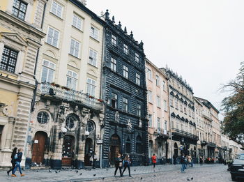 People walking on street in city against clear sky