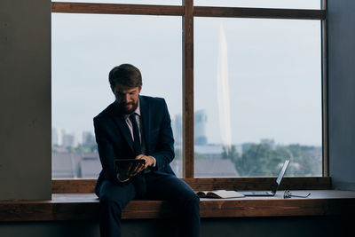 Young man using mobile phone while sitting on table