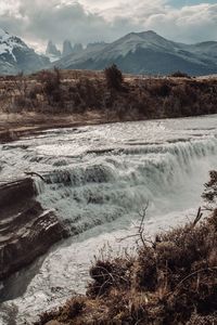 Scenic view of waterfall against mountains
