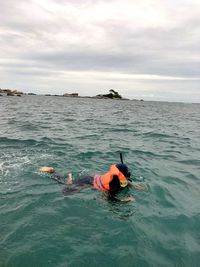 Rear view of man swimming in sea against sky