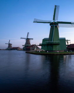 Traditional windmill by river against sky