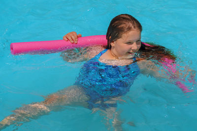 High angle view of girl with noddle looking away in swimming pool