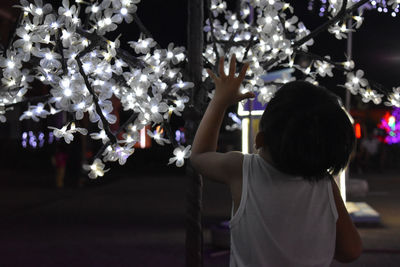 Rear view of girl standing by christmas tree