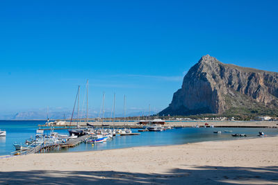 Sailboats moored on sea against clear blue sky