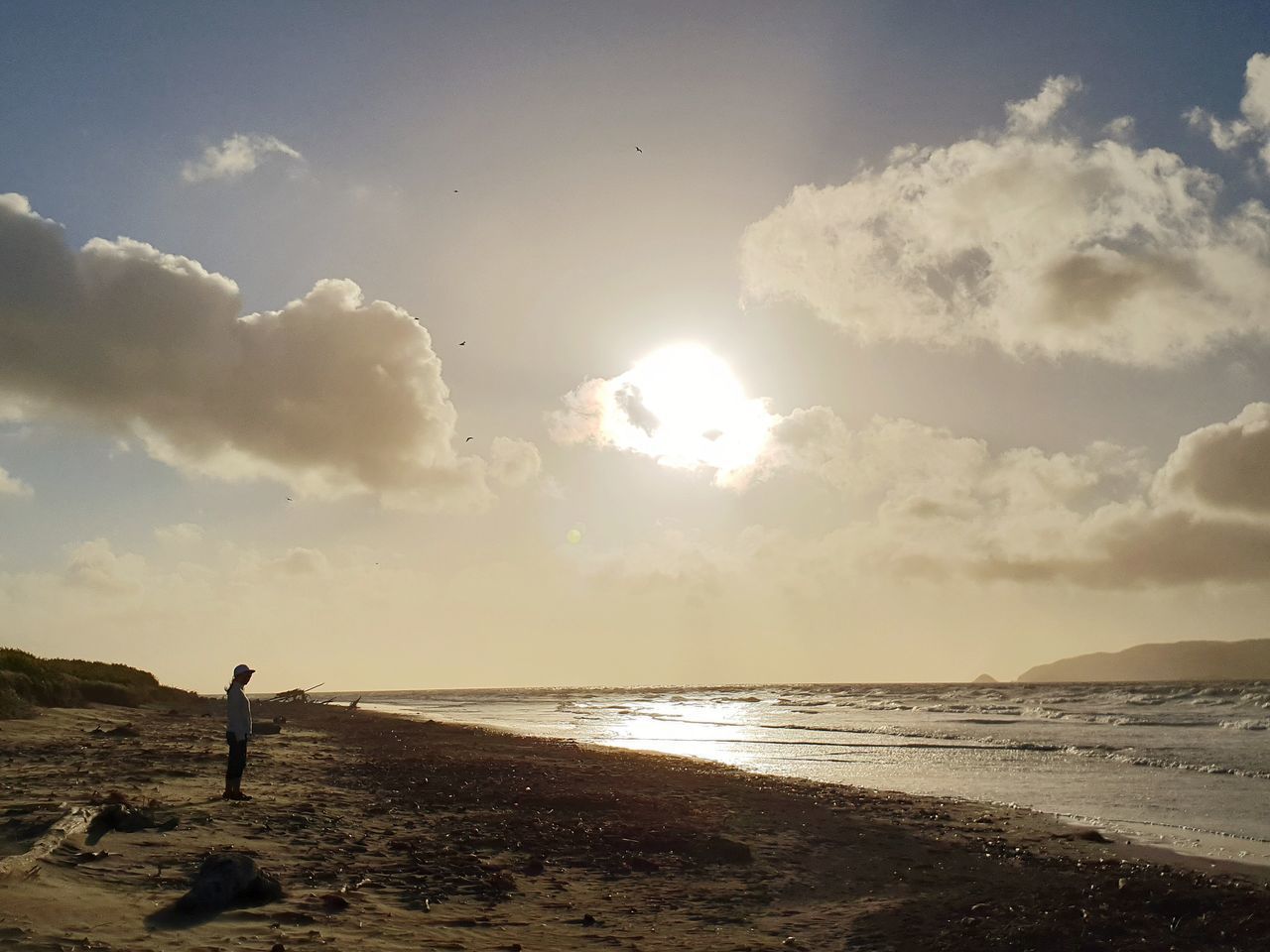 MAN STANDING ON BEACH AGAINST SKY