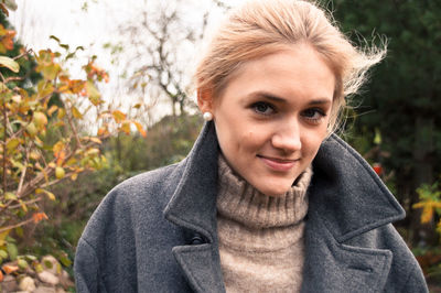 Portrait of smiling young woman wearing warm clothing in park