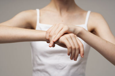 Midsection of woman with hands standing against white background