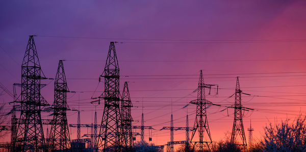 Panorama, silhouette of high voltage power lines against a colorful sky at sunrise or sunset.