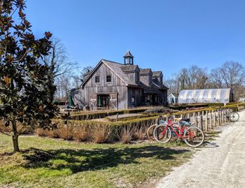 Bicycle parked on field by building against sky