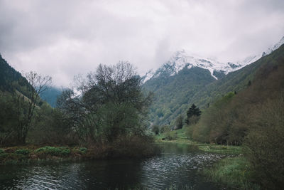 Scenic view of river by mountains against sky