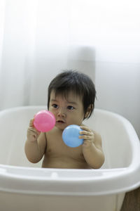 Cute baby sitting in bathtub at home