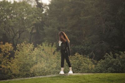 Full length of woman standing amidst trees in forest