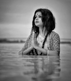 Woman with hands clasped standing in river