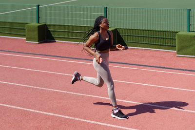 African american woman practices running technique to get success at upcoming competitions side view