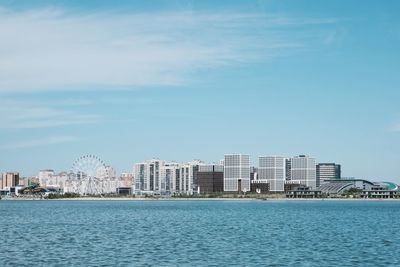 Sea by buildings against sky in city