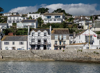 Houses in front of river by town against sky