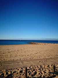 Scenic view of beach against clear blue sky