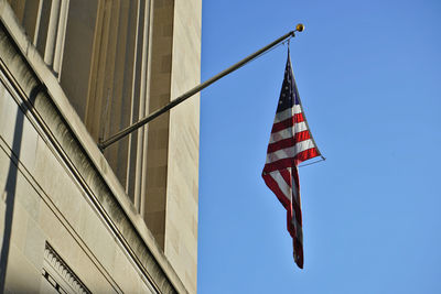 Low angle view of flag on building against clear blue sky
