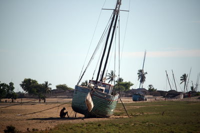 Boats moored on field against clear sky