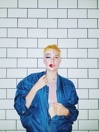 Portrait of young woman standing against wall