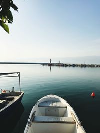 Boats moored in sea against clear sky