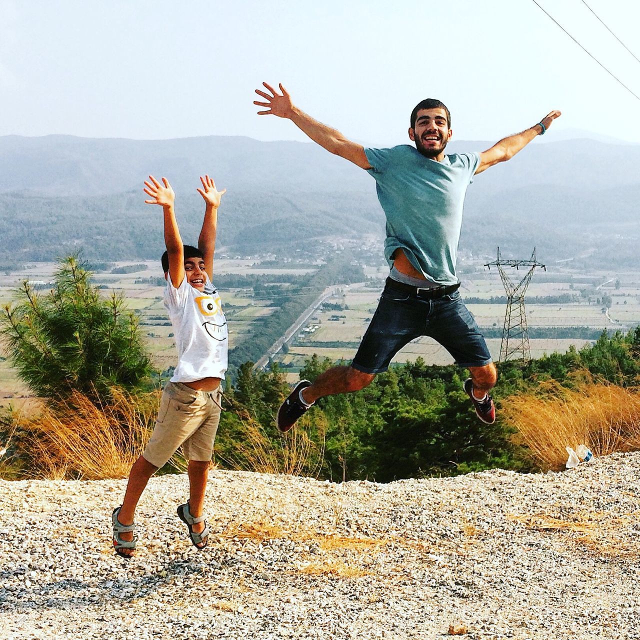 full length, casual clothing, lifestyles, leisure activity, young women, jumping, young adult, arms raised, arms outstretched, happiness, person, mid-air, togetherness, playing, focus on foreground, clear sky, plant, day, carefree, long hair, outdoors, fun, enjoyment, sky, sunbeam, looking at camera