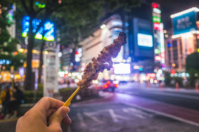 Close-up of hand holding illuminated lighting equipment in city
