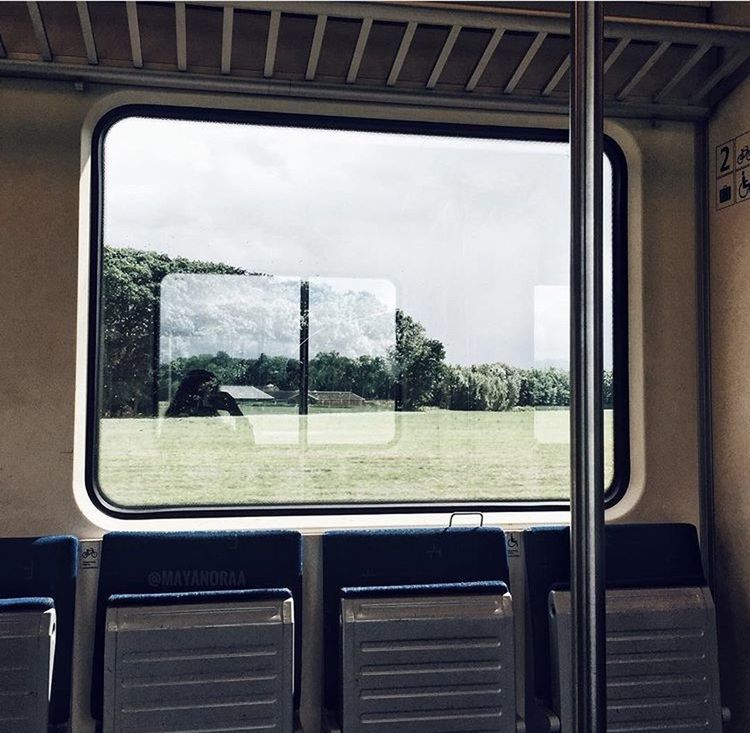 TRAIN AGAINST SKY SEEN THROUGH WINDOW OF RAILROAD STATION