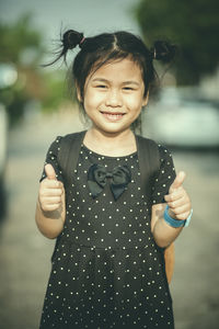 Portrait of smiling girl gesturing while standing outdoors
