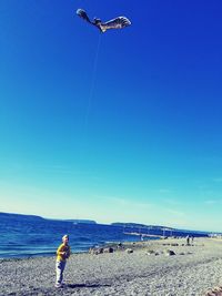 Man flying kite on land against blue sky