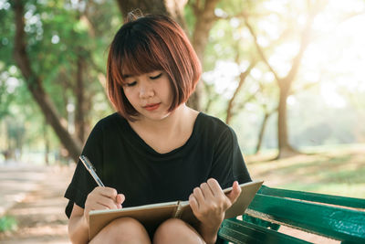 Young woman looking away while sitting on bench