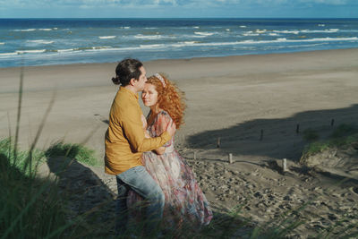 Side view of couple standing at beach