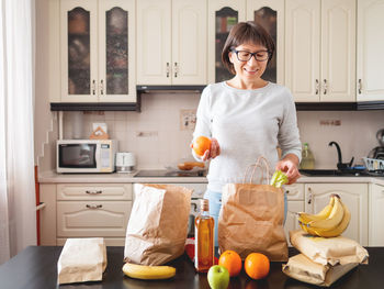 Woman sorts out purchases in the kitchen. grocery delivery in paper bags. 