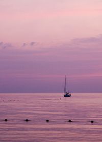 Sailboat sailing on sea against sky during sunset