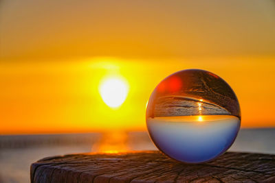 Close-up of crystal ball on beach during sunset