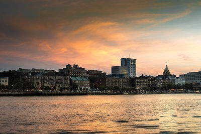 Buildings at waterfront during sunset