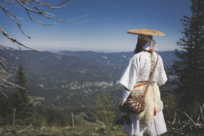 Rear view of man standing on mountain against sky